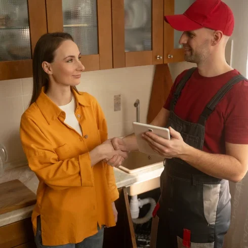 Repairman holding tablet in kitchen discussion.